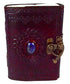 A decorative leather-bound journal with intricate designs and a blue gemstone on the cover, featuring a heart-shaped clasp.
