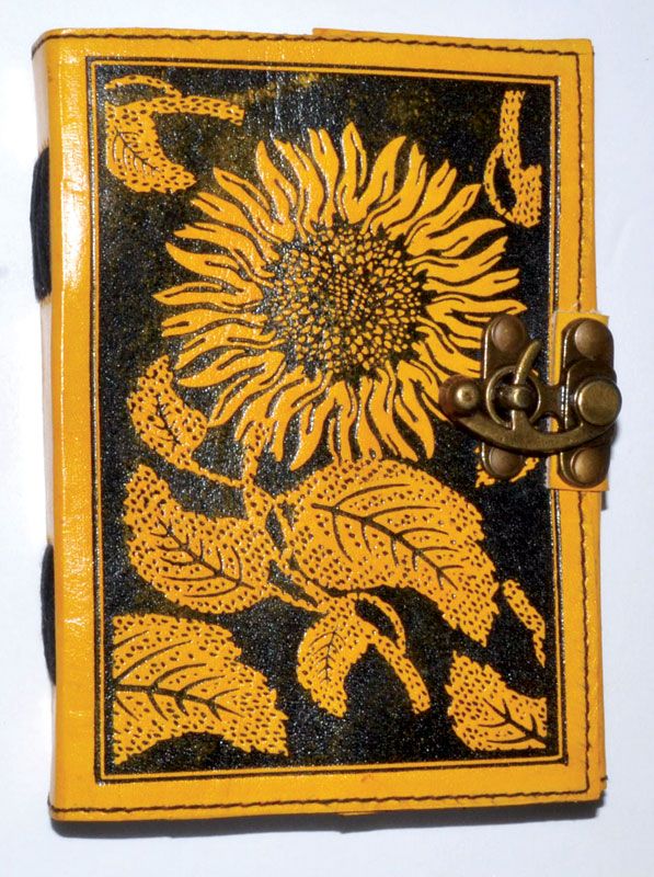 Leather-bound blank journal with embossed sunflower design on the cover and a decorative latch closure, suitable for use as a grimoire or spell journal.