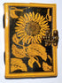 Leather-bound blank journal with embossed sunflower design on the cover and a decorative latch closure, suitable for use as a grimoire or spell journal.