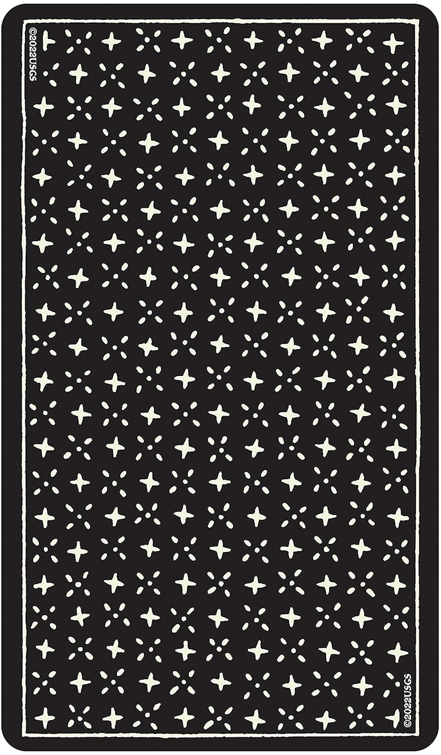 Dark surface showing the back design of the Glow in the Dark Tarot cards — a repeating pattern of small white stars on black.
