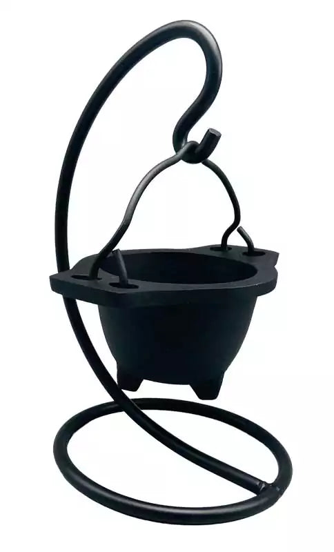 Hanging cast iron cauldron incense burner suspended on a decorative black metal stand — Gothic swinging cauldron design for altar smudging and resin work.