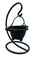 Hanging cast iron cauldron incense burner suspended on a decorative black metal stand — Gothic swinging cauldron design for altar smudging and resin work.