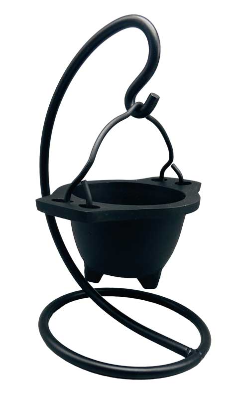 Hanging cast iron cauldron incense burner suspended on a decorative black metal stand — Gothic swinging cauldron design for altar smudging and resin work.