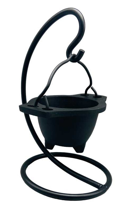 Hanging cast iron cauldron incense burner suspended on a decorative black metal stand — Gothic swinging cauldron design for altar smudging and resin work.