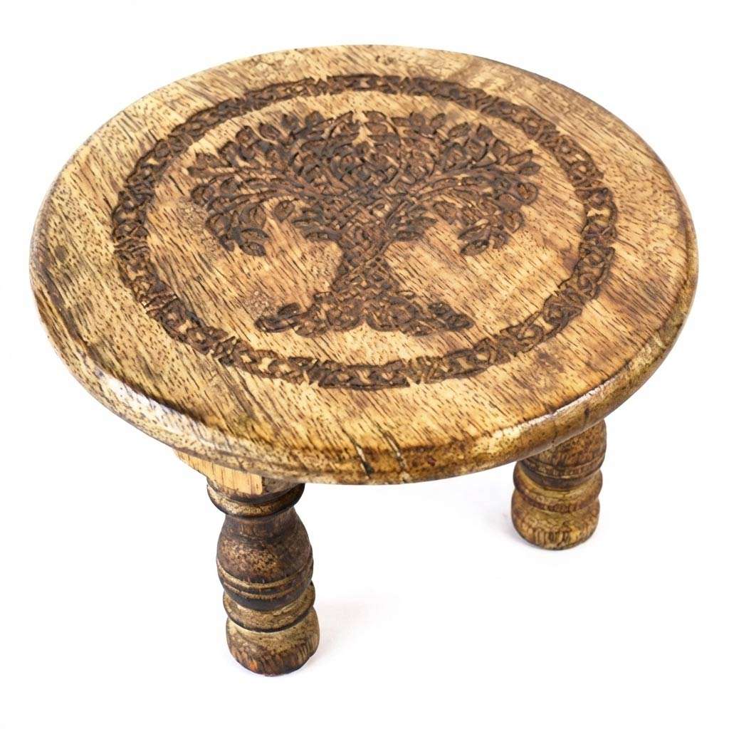 6-inch round wooden altar table with a carved Tree of Life design on the surface and three sturdy wooden legs supporting it.