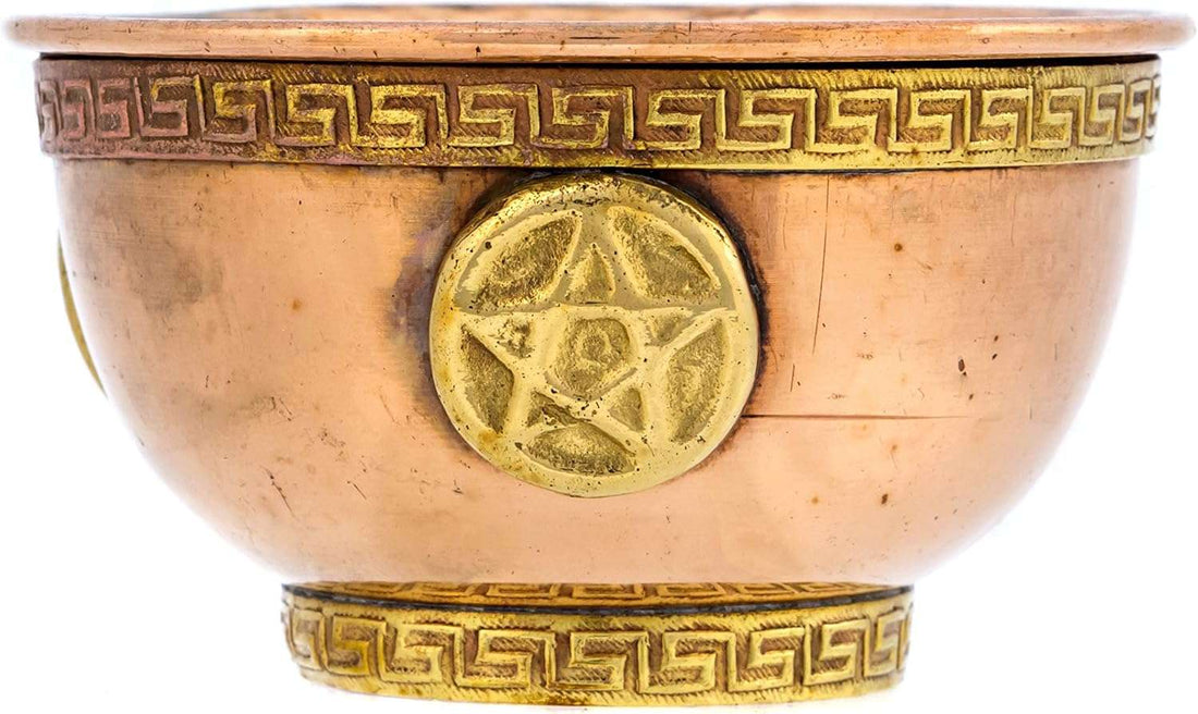 A decorative copper bowl featuring a gold-colored pentagram emblem and a Greek key design around the rim. The bowl has a smooth finish and a rounded shape.