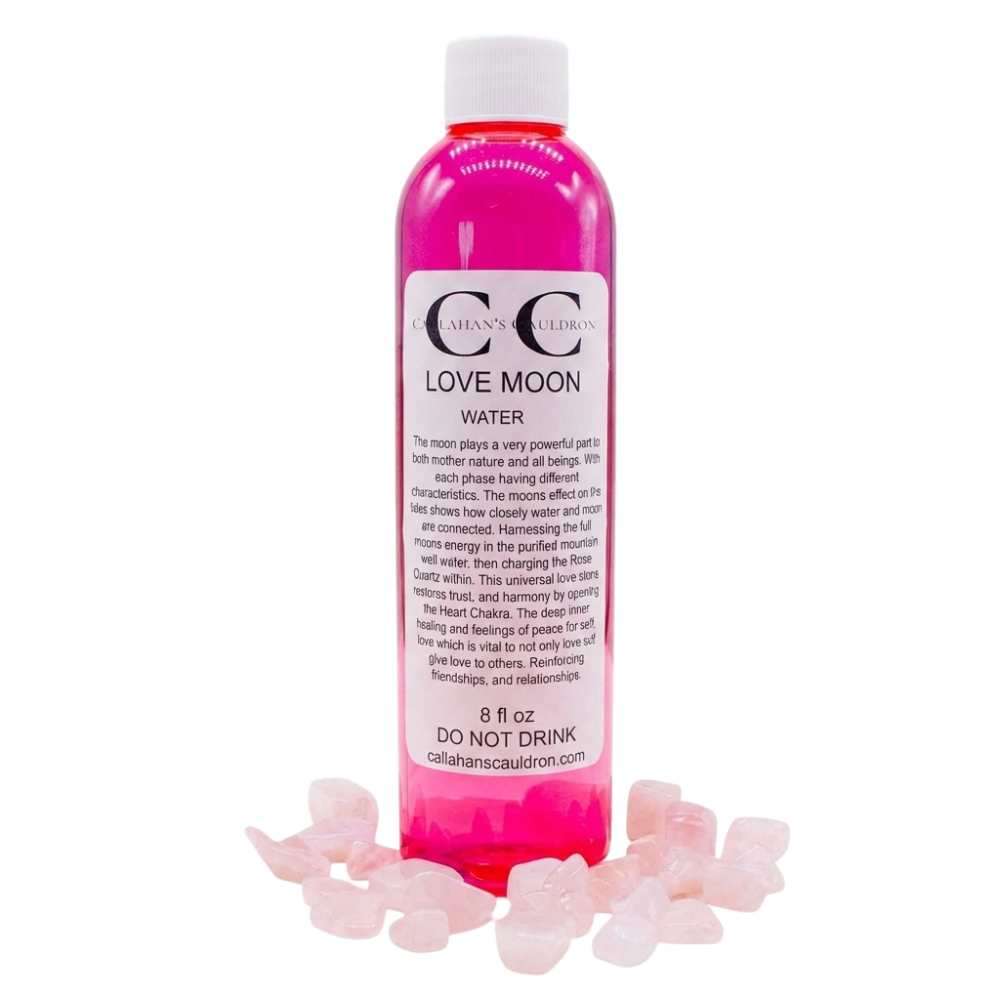 A bottle of pink liquid labeled "Love Moon Water" surrounded by small pink crystals. The label includes a warning not to drink the contents.