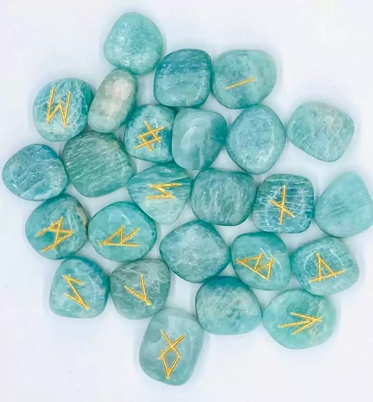 25-piece amazonite Elder Futhark rune set with teal gemstone tiles engraved with gold-filled runic symbols arranged beside a wooden box for Norse divination practice.