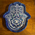 Decorative Hamsa hand with blue glittery border on a wooden surface