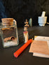 Handmade money spell jar with cork lid, chime candle, and apothecary match bottle.