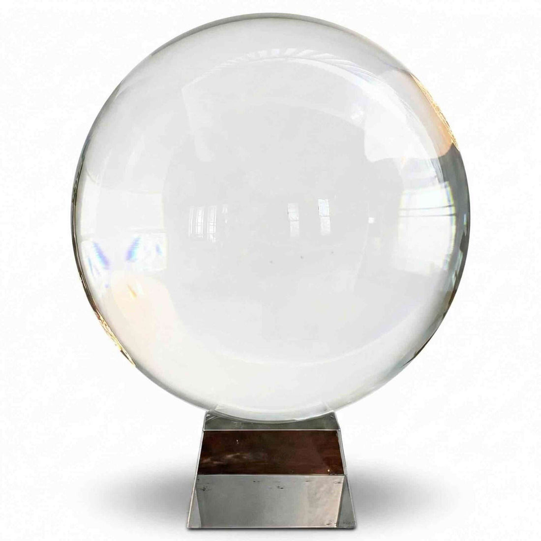 A large 200mm clear crystal ball on a metallic display stand reflecting light and creating visual distortions — an 8-inch polished quartz sphere for scrying, meditation, and altar display.