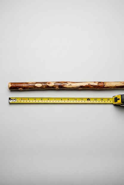 Rustic hardwood broom handle beside a yellow tape measure on a light background
