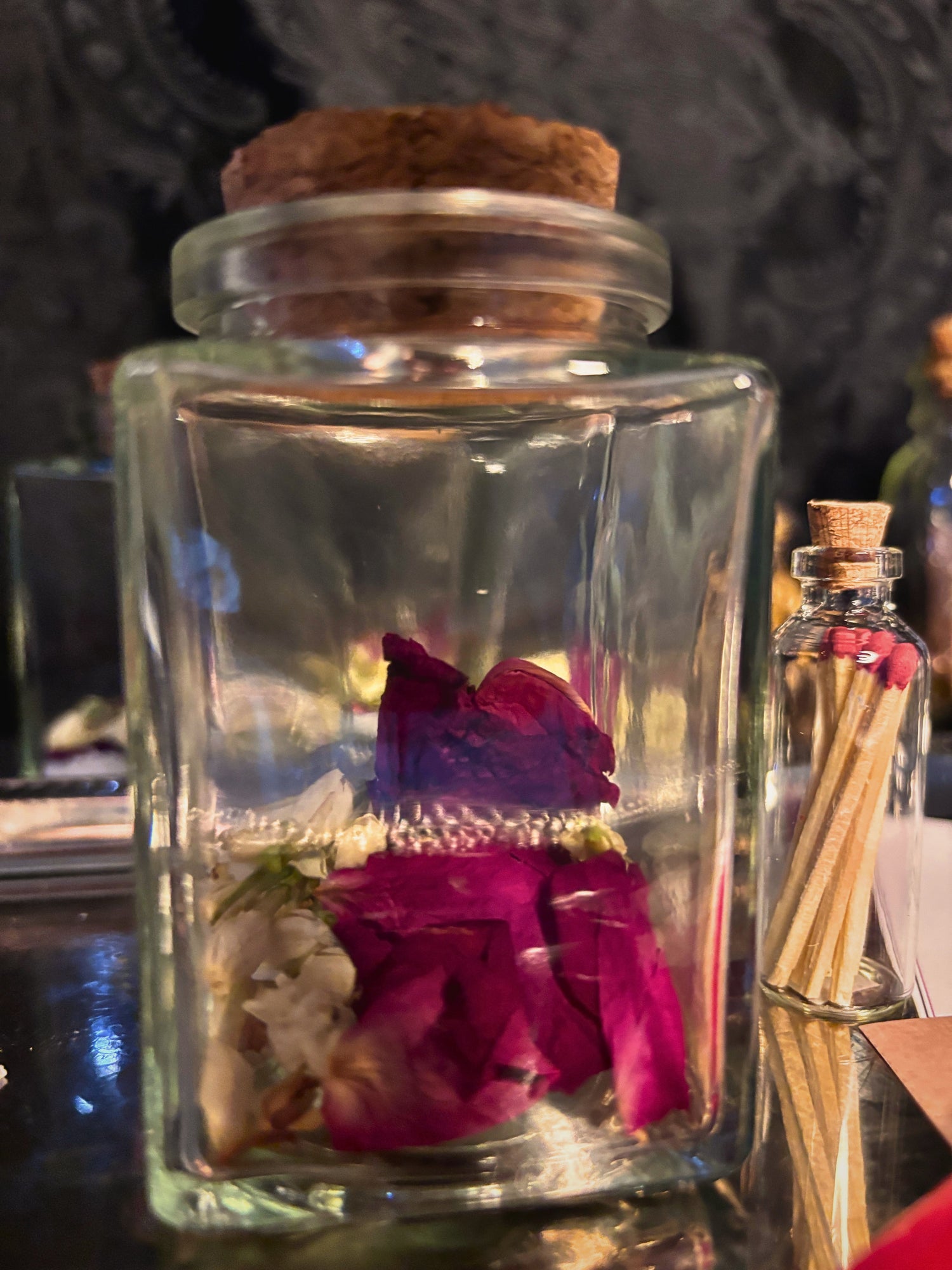 A love spell jar with a corked top containing rose petals and jasmine.