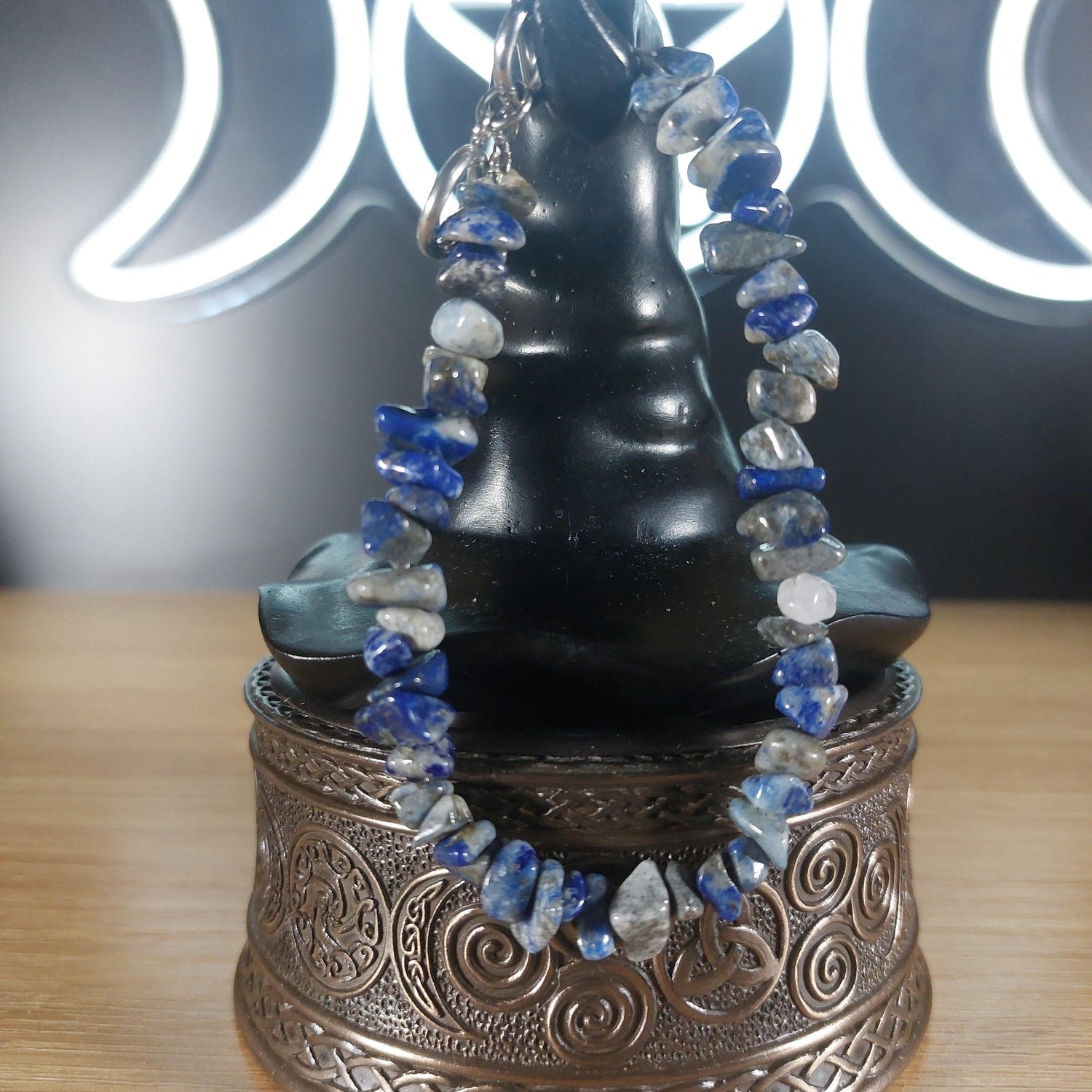 Lapis Lazuli crystal chip bracelet with blue and gray stones, stainless steel toggle, on an ornate silver box.