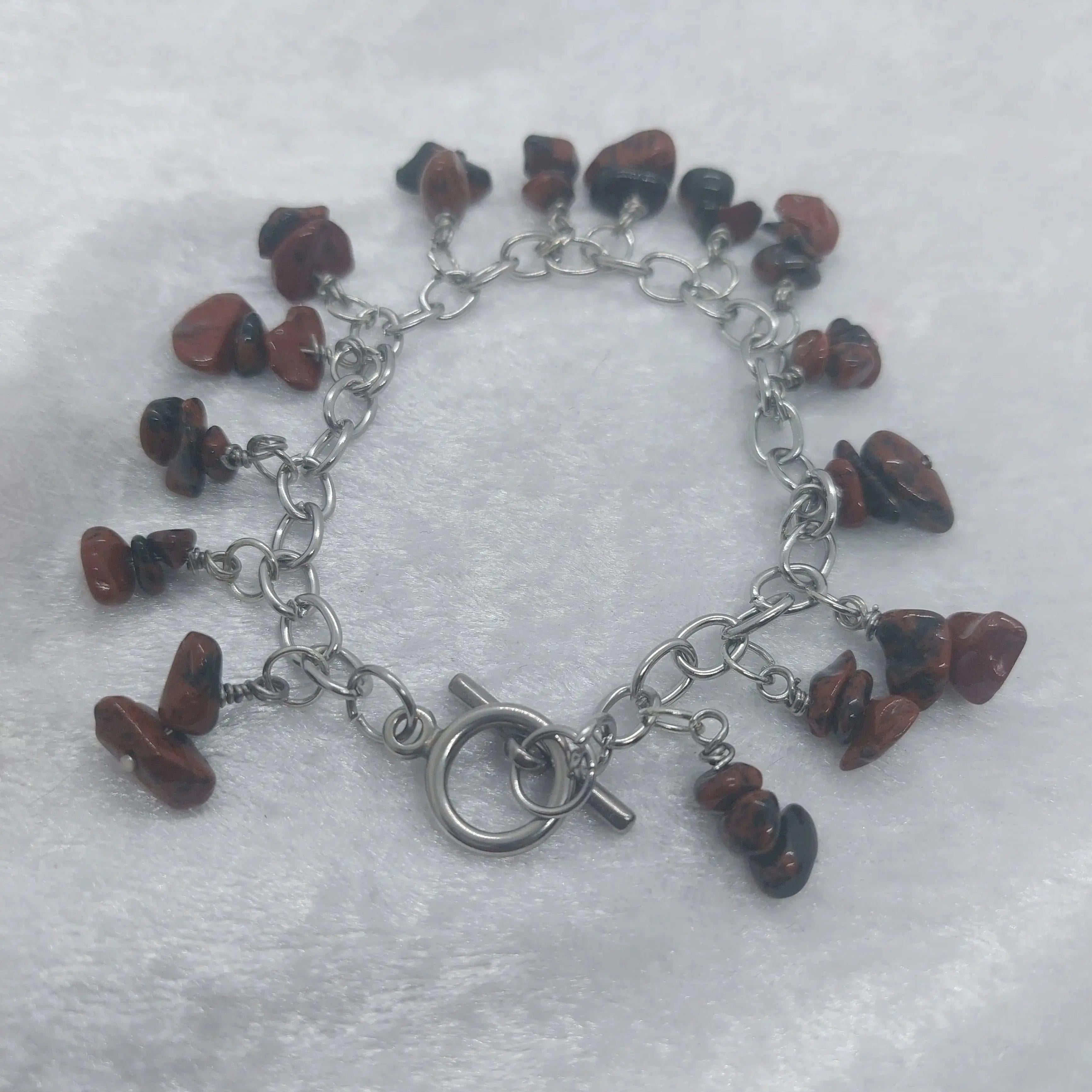 Mahogany obsidian chip bracelet with a stainless steel chain and toggle clasp on a white surface.