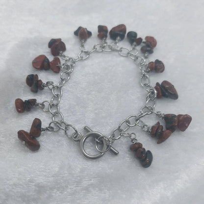 Mahogany obsidian chip bracelet with a stainless steel chain and toggle clasp on a white surface.