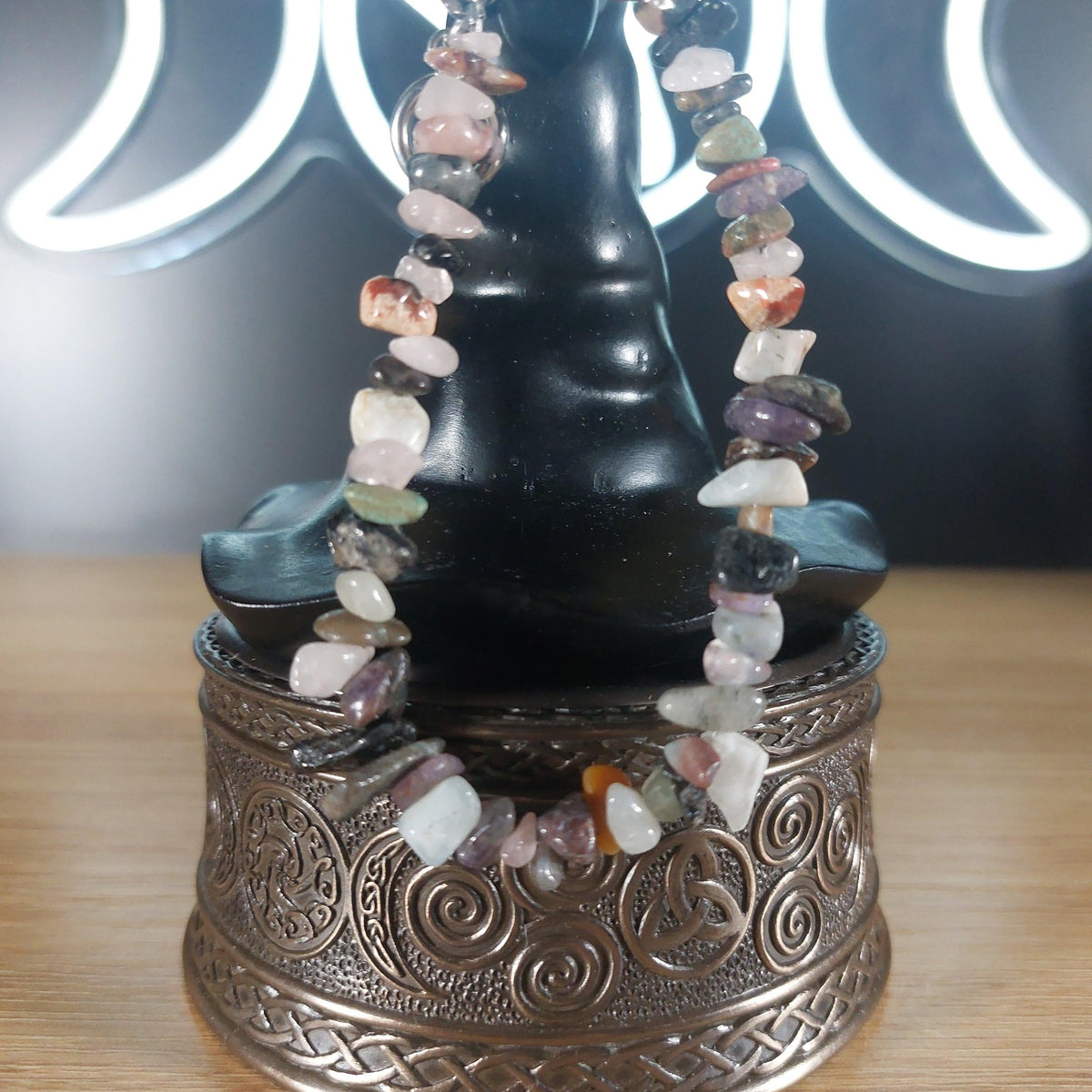Mixed quartz crystal chip bracelet with colorful stones and a stainless steel toggle clasp, displayed on a decorative stand.