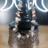 Mixed quartz crystal chip bracelet with colorful stones and a stainless steel toggle clasp, displayed on a decorative stand.