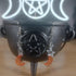 Orange glass moon and silver star dangle earrings hanging from a black cauldron.