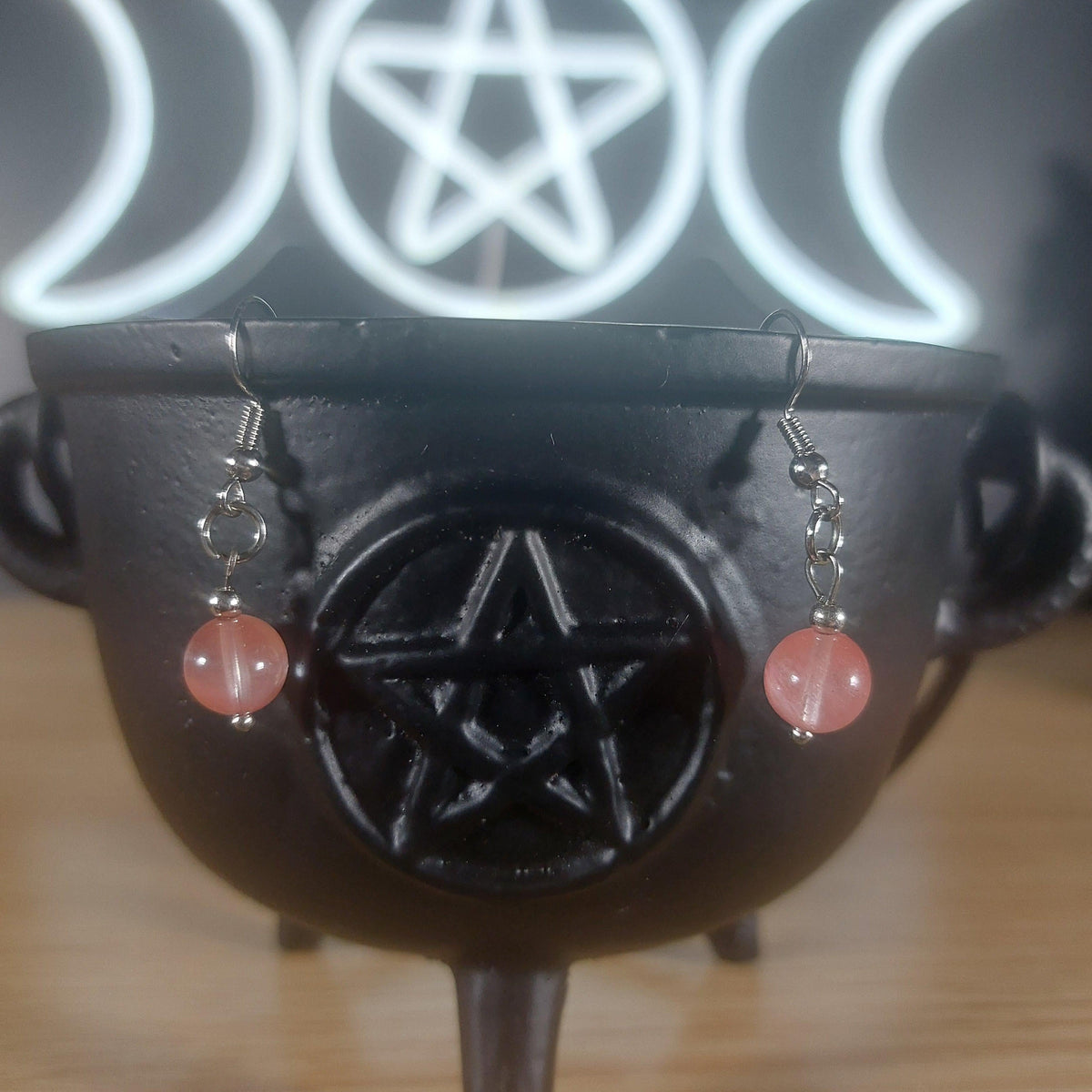 Pink rose quartz crystal beaded dangle earrings on a black cauldron with a Triple Moon pentacle symbol.