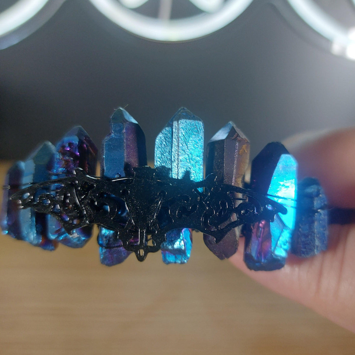 Metallic blue treated quartz crystal crown with wire wrap on a black headband.
