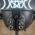 Antique bronze skeleton dangle earrings with black oval resin cabochons, displayed in a black cauldron.