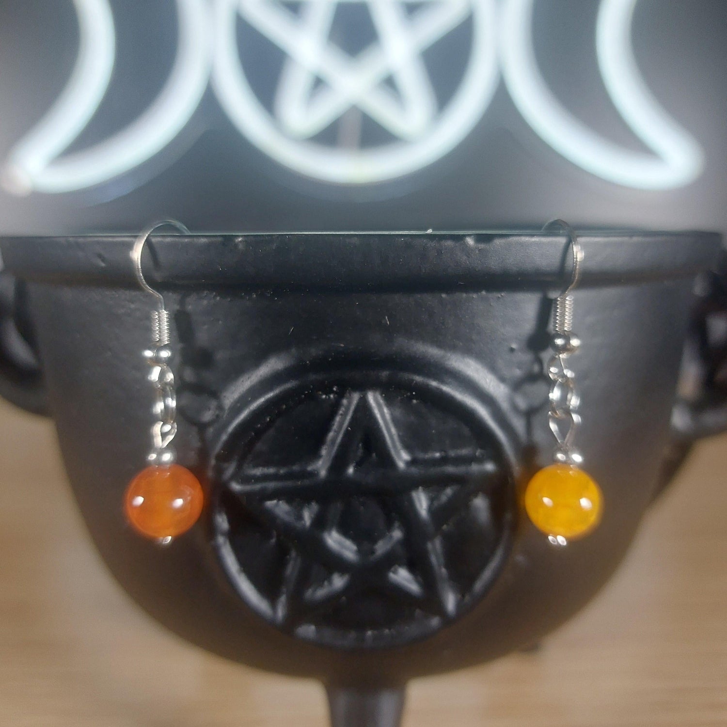 Yellow chalcedony crystal beaded dangle earrings with silver hooks, displayed on a black cauldron.