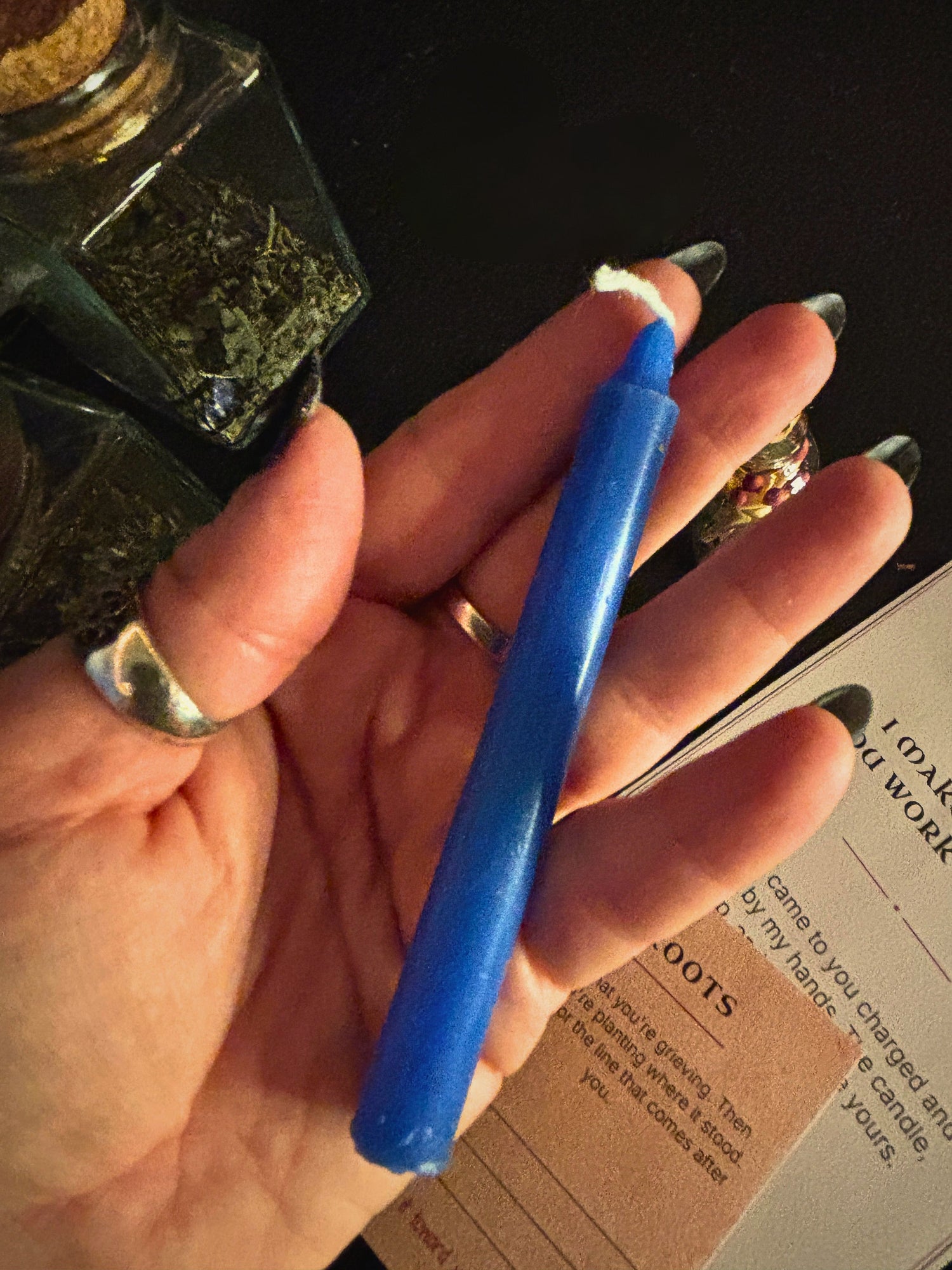 A hand holding a 4" blue taper candle