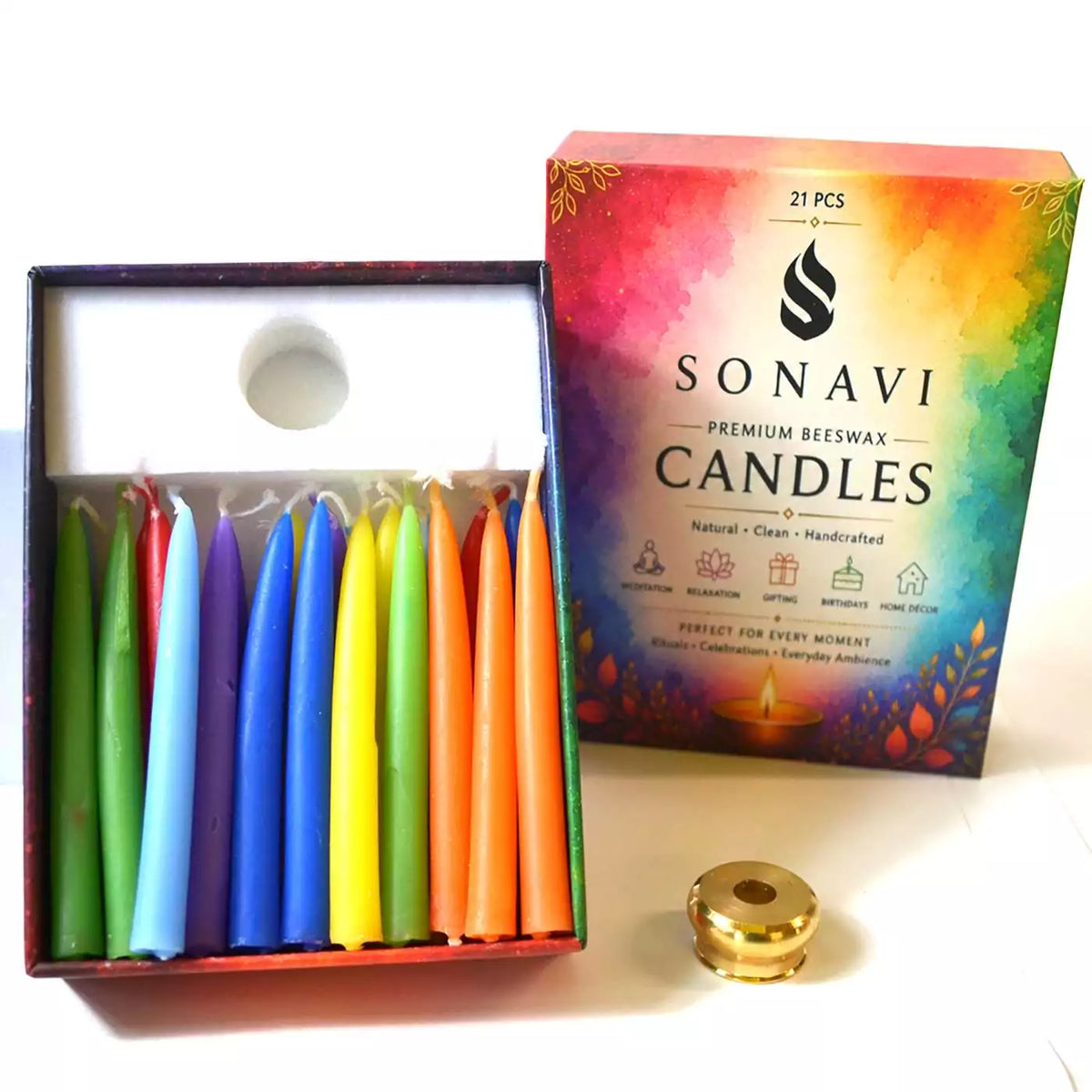 Open box of 21 assorted-color beeswax taper candles with white wicks beside the printed box lid reading Premium Beeswax Candles and a small brass candle holder