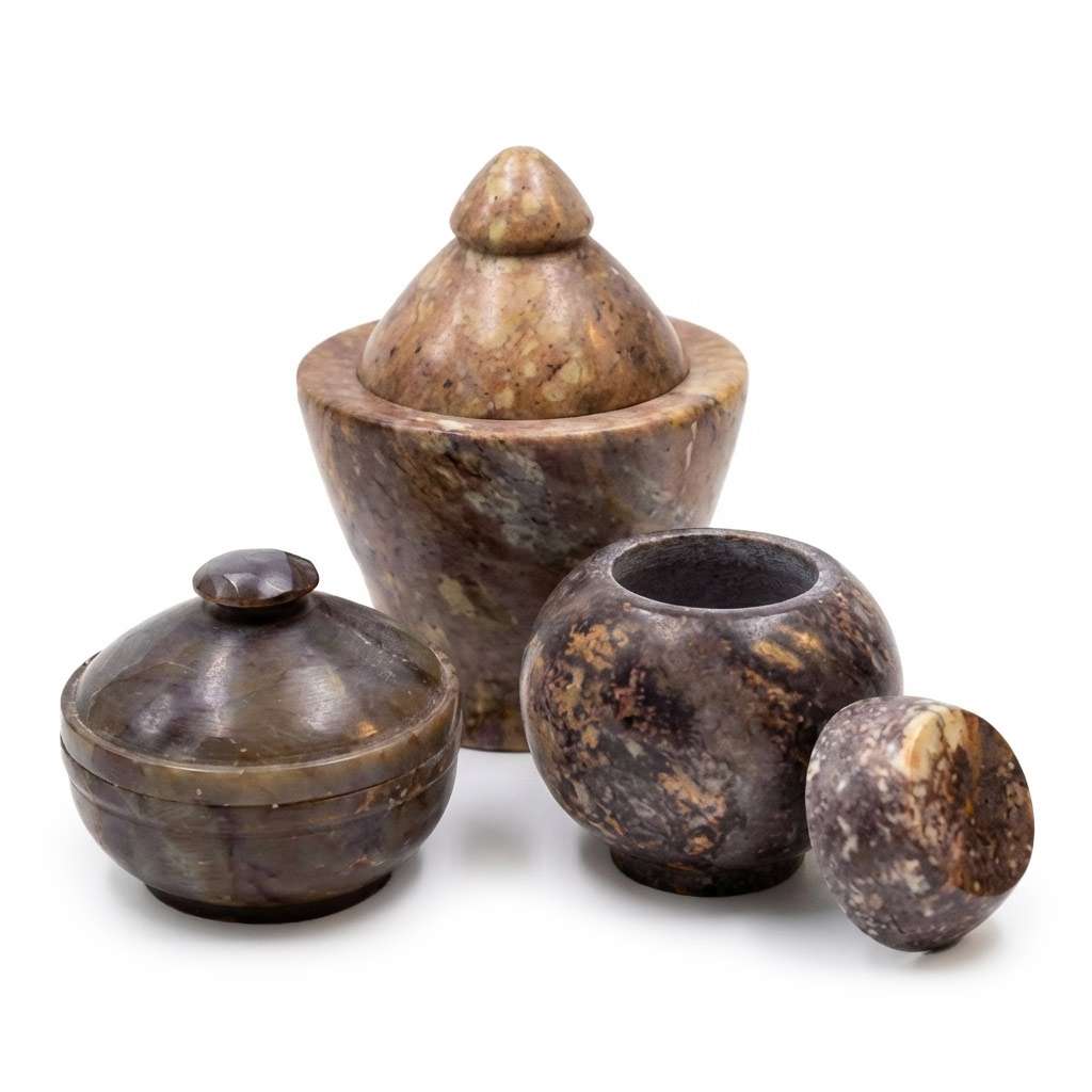 A collection of four decorative stone containers in various shapes and sizes, showcasing intricate patterns and earthy tones.